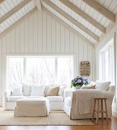 a living room with white furniture and wood flooring, along with a large window