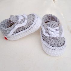 two crocheted baby shoes sitting on top of a white tile floor next to each other