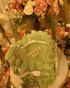 a green frosted cake sitting on top of a table next to flowers and candles