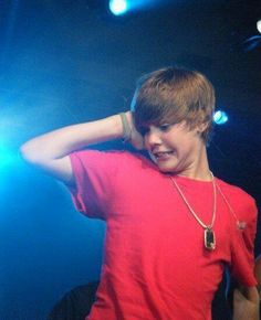 a boy in a red shirt is holding his hands behind his head