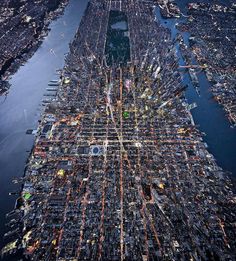 an aerial view of a city with lots of buildings and streets at night, as seen from the air