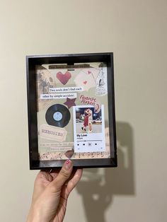 a person holding up a framed cd case