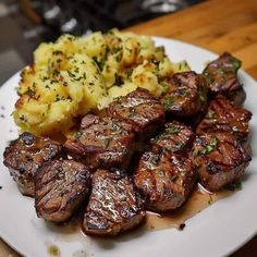 a white plate topped with meat and potatoes