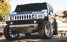 a silver hummer truck parked in front of a fence