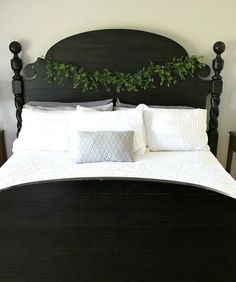 a black headboard with white pillows and green garland on the top, along with two nightstands