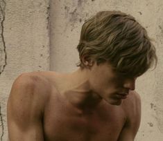 a shirtless young man holding a cell phone