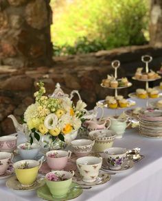 a table topped with lots of tea cups and saucers filled with different types of flowers