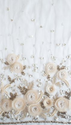 an embroidered white fabric with flowers and pearls on it's edge, as well as sequins