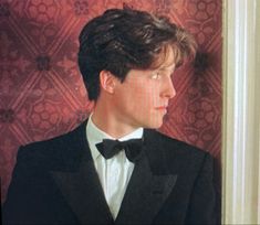 a young man in a tuxedo and bow tie looking off into the distance