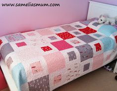 a small bed with a quilt on it in a pink and white room next to a dresser