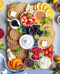 an assortment of cheeses, crackers, fruit and nuts on a cutting board