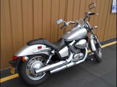 a silver motorcycle is parked in front of a brown wall and yellow lines on the ground