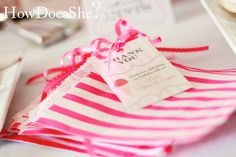 a pink and white striped bag with a tag on it sitting on a table next to other items