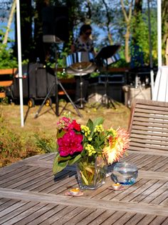 two vases filled with flowers sitting on top of a wooden table next to a grill