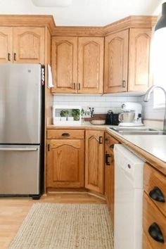 a kitchen with wooden cabinets and stainless steel refrigerator freezer combo in the center, along with an area rug on the floor