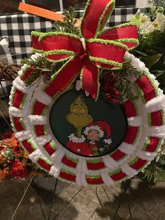 the grinch christmas ornament hanging on a table with flowers and greenery