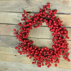 a red berry wreath is hanging on a wooden wall