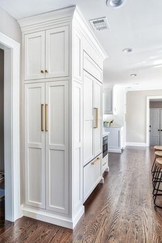 a kitchen with white cabinets and wood floors