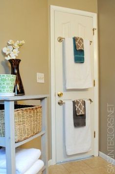 two towels are hanging on the door and in front of it is a basket with flowers