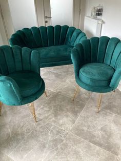 three green velvet chairs with gold legs in a living room or dining area, one is shaped like an oval couch and the other is shaped like a chair