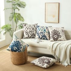 a living room with a white couch and pillows on the floor next to a potted plant