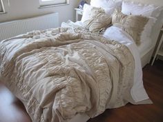 an unmade bed with white linens in a bedroom next to a lamp and window