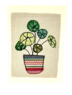 a potted plant with green leaves in it on a white wall hanging ornament