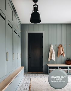 a hallway with blue cabinets and a bench next to it, along with a black door