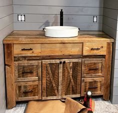 a bathroom vanity made out of wood with a bowl on the top and other items around it