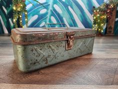 an old metal box sitting on top of a wooden floor next to christmas trees and lights