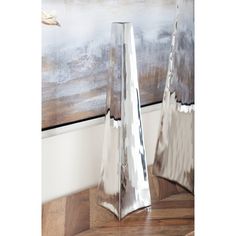 two silver vases sitting on top of a wooden table in front of a painting