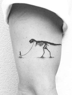 a small tattoo of a dinosaur pulling a man on a string by it's tail