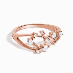 a rose gold ring with white stones on the side and an arrow design in the middle