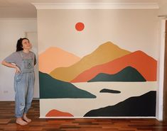 a woman standing in front of a painting on the wall next to a wooden floor