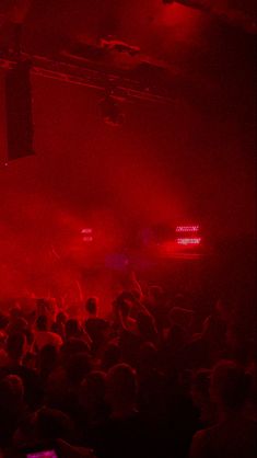 a crowd of people in a dark room with red lights