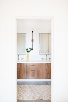 a bathroom with two sinks, mirrors and a vase filled with flowers on the counter