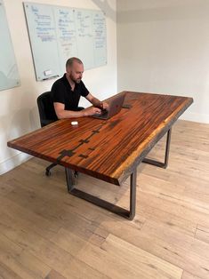 a man sitting at a wooden table with a laptop computer on it's side