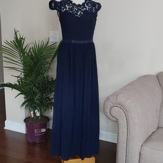 a dress is hanging on a hanger in front of a couch and potted plant