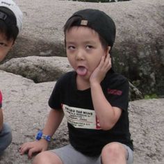 two young boys sitting on rocks with their mouths open