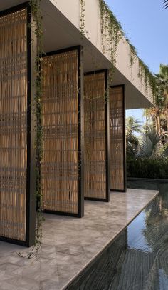 an outdoor room with bamboo screens on the wall and water in the pool behind it