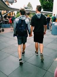 two men walking down a sidewalk holding hands