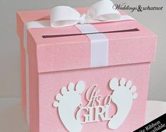 a pink box with white bows on the top and it's its a girl