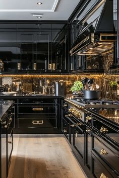 a kitchen with black cabinets and marble counter tops, gold trim on the backsplash