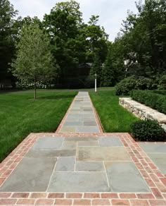 a long brick walkway with grass and trees in the background