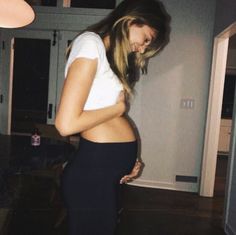 a woman standing in a room with her stomach exposed