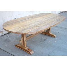 a wooden table sitting on top of a cement floor next to a white brick wall