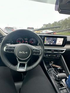 the interior of a car with dashboard, steering wheel and other vehicles in the background