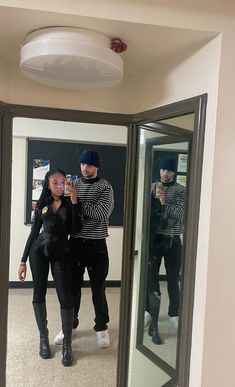 two people standing in front of a mirror taking a selfie with their cell phone