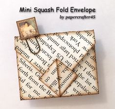 an origami square folded envelope on top of a piece of paper with the words mini squash fold envelope