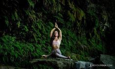 a woman sitting on top of a rock next to a lush green forest